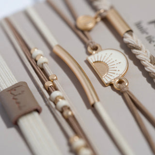 K'lani "Rise" Cream and Tan With Gold and Sun Hair Tie Bracelets
Close-up of a bracelet with decorative elements on a neutral background