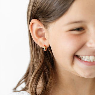Pip Pop Post Earrings - Smiley Face Hoop
Close-up of a girl wearing colorful earrings with a plain background