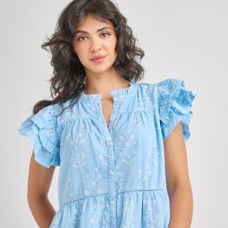 Pink Chicken Womens Kalani Ruffle Dress - Blue Dewdrop Block Print
Woman wearing a light blue dress with floral patterns on a plain background