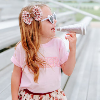Sweet Wink Football Cutie Tulle Bow Clip Young girl with a megaphone wearing a pink top and decorative headband.
