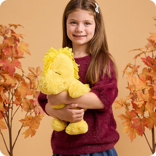 Woodstock Warmies
Young girl holding a yellow plush toy with autumn leaves in the background